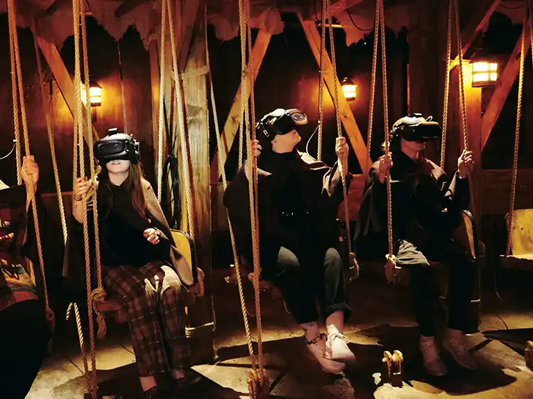 Immersive experiences | people sitting on wooden swings wearing VR glasses.