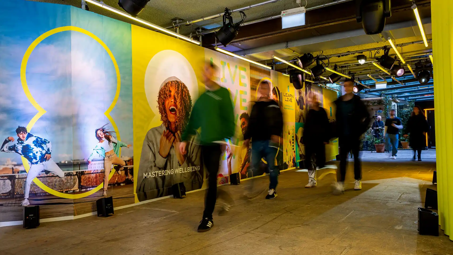Experiential marketing | People walking through a hallway lined with posters